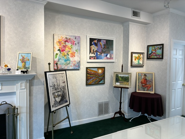 A wall of framed original paintings inside Frame House Gallery