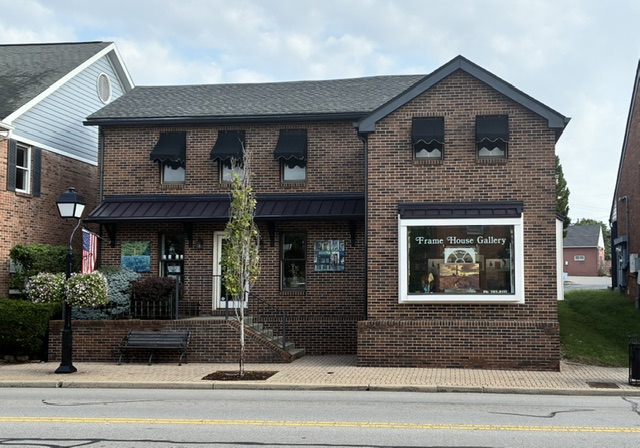The Frame House Gallery brick building on Montgomery Road, with benches and flowers out front