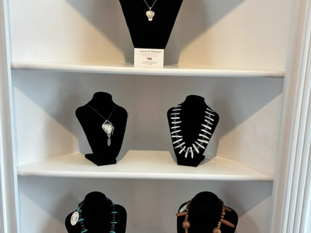 Necklaces on black velvet busts across the white display shelves