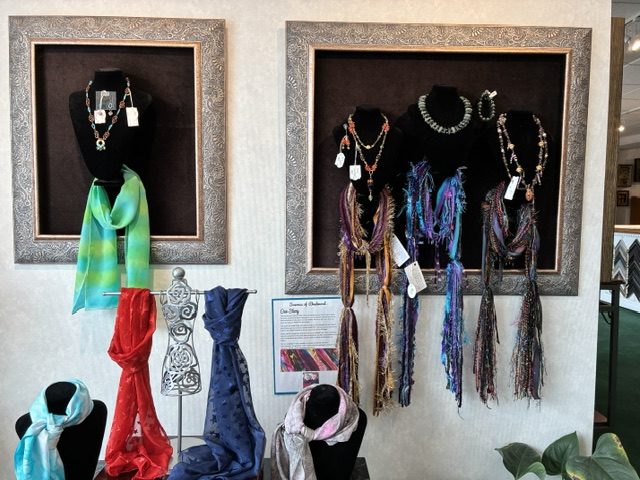 Fringed and beaded scarves hung inside framed shadow boxes